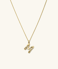 Organic Dôme Liquid Letter Pendant Necklace featuring a gold chain with a diamond-accented letter 'M' pendant, highlighting its unique, organic design.