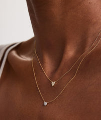 Person wearing a Mini Heart Pavé Diamond Necklace, showcasing a close-up of the heart-shaped pendant on a delicate chain.