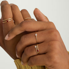 Close-up of hands wearing the Gemstone Trillion Stacker Ring, a 14k solid gold ring set with a white topaz gemstone.
