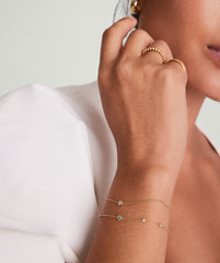 Close-up of a woman's hand wearing the Solo Diamond Bracelet, a solid gold piece with a round-cut diamond in a bezel setting.