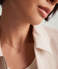 Close-up of a womanâs neck wearing a 14k gold handcrafted Birthstone Charm necklace, highlighting the intricate design and elegance of the jewelry.