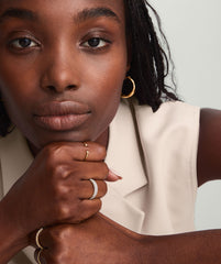 Woman's hand resting on chin, showcasing the Diamonds Open Ring with bezel-set diamonds and an open design, highlighted among other jewelry.