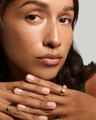 Young person displaying manicured nails and gold rings, highlighting the Sabine Open Signet Pinky Ring with pavé diamonds.