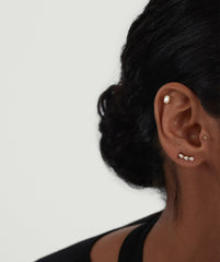 Close-up of a woman's ear wearing Lab Grown Diamond Pear Climber Studs, showcasing a trio of diamonds elegantly climbing along the earlobe.