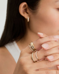 Close-up of a woman's hands showcasing the Dôme Figure Slim Ring, a handcrafted 14k gold piece with sleek curves and an architectural design.