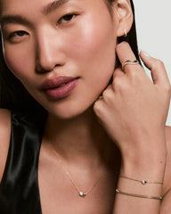 Young woman wearing the Better Half Heart Bracelet, showcasing delicate gold jewelry, including a fine necklace and matching gold bracelets, accentuating her elegant, modern style.