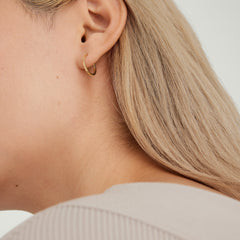 Close-up of a woman's ear wearing Easy Small Hoops, handcrafted 14k gold earrings with a clicker closure for daily comfort and security.