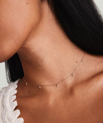 Woman showcasing Multi Station Diamond Necklace, a handcrafted 14k gold choker adorned with five responsibly sourced diamonds, highlighting its dainty yet edgy design.