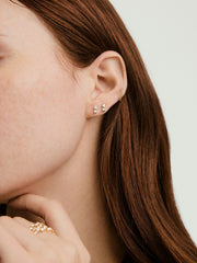 Close-up of a woman's ear adorned with droplet-style lab grown diamond stud earrings, designed to move and reflect light, highlighting their elegance.