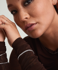 Close-up of a woman wearing a Lab Grown Sapphire Tennis Bracelet, showcasing its clear, sparkling stones set in sterling silver, highlighting its elegant, delicate design.