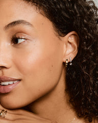 Woman wearing Simone Drop Earrings featuring a small gold hoop and a drop earring with three bezel set lab-grown sapphires, complemented by a larger dangling gem.