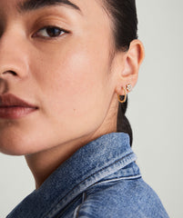Close-up of a woman's face showcasing Pavé Diamond Small Hoops, handcrafted in recycled 14k gold, worn on her ear.