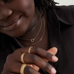 Woman wearing a black shirt, showcasing the Pavé Diamond Linked Necklace with two interlinked gold rings, symbolizing personal connections, adorned with Kimberley Process compliant diamonds.
