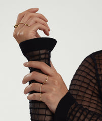 Close-up of a woman's hand wearing the Sculpture Ring, showcasing its artistic design. The ring is complemented by a gold bracelet on the wrist.