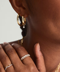 Close-up of a woman's ear adorned with a Mini Pear Diamond Hoop Charm in 14k solid gold, featuring a pear-shaped diamond.
