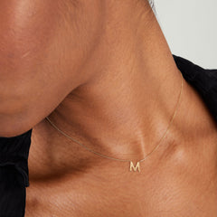 Person wearing a gold letter necklace on a chain, showcasing the elegant design of the Letter Necklace, a must-have fashion accessory for any jewelry collection.