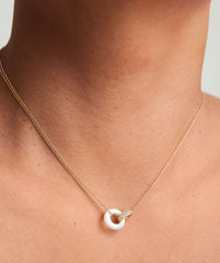Linked Pavé Diamond Pearl Necklace on a person's neck, showcasing two interlinked rings with diamonds and mother of pearl, symbolizing personal bonds.