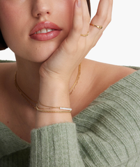 Close-up of a woman wearing a Tiny Pearl Bracelet, highlighting the delicate pearls and gold chain on her wrist.