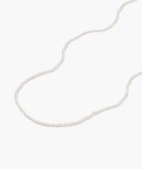 Micro Pearl Necklace on white surface, featuring delicate freshwater pearls and handcrafted in 14k gold, perfect for elevating any outfit.