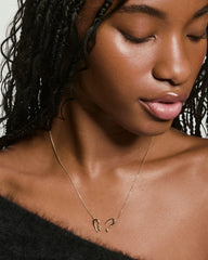 Young woman wearing the Heart to Heart Necklace, featuring two abstract gold pendants forming a modern heart shape, suspended on a delicate gold chain.