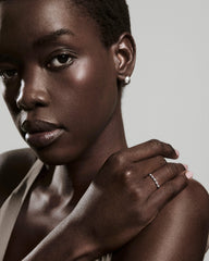 Charlotte Crest Stacker Ring on woman's hand, featuring delicate sapphires and curved edges. The ring is highlighted by her calm pose and minimalistic studio setting.