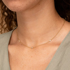 Woman wearing the Satellite Necklace, a handcrafted vermeil piece with white sapphires, designed to complement both casual and formal attire.