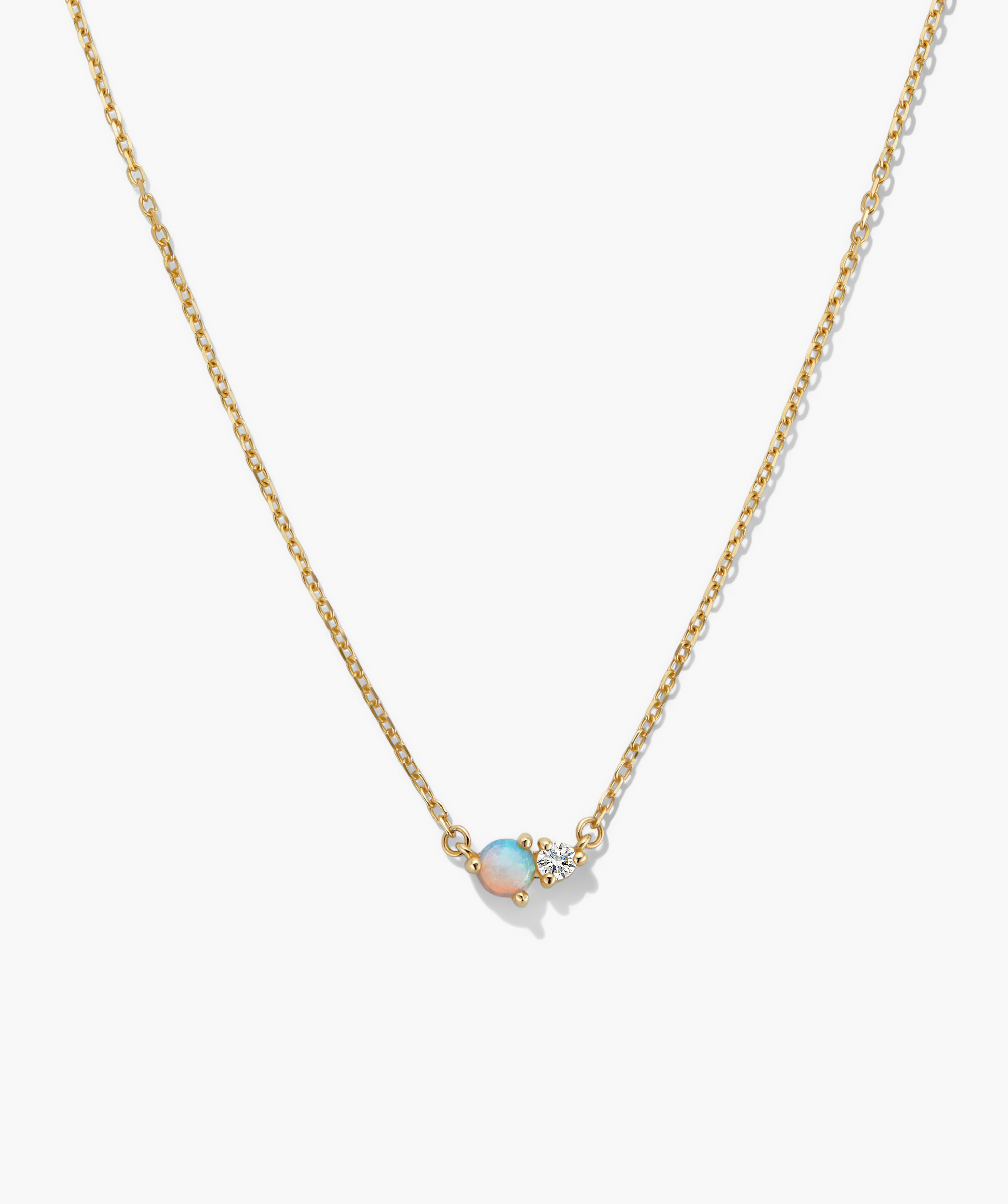 Beverly Necklace: A minimalist gold-tone chain with a central pendant featuring a round opal and clear faceted gem, ideal for layering or wearing solo.