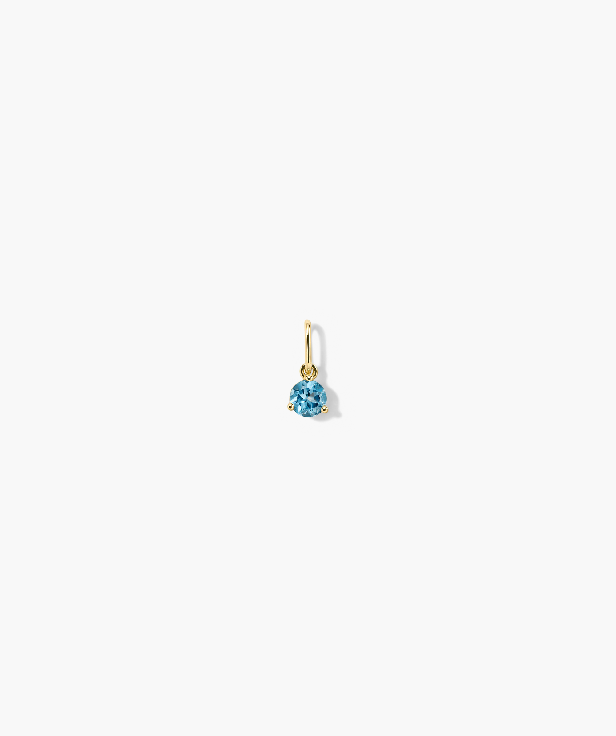 Birthstone Charm: Close-up of a blue gem set in a handcrafted 14k gold earring, perfect for birthdays or special occasions.