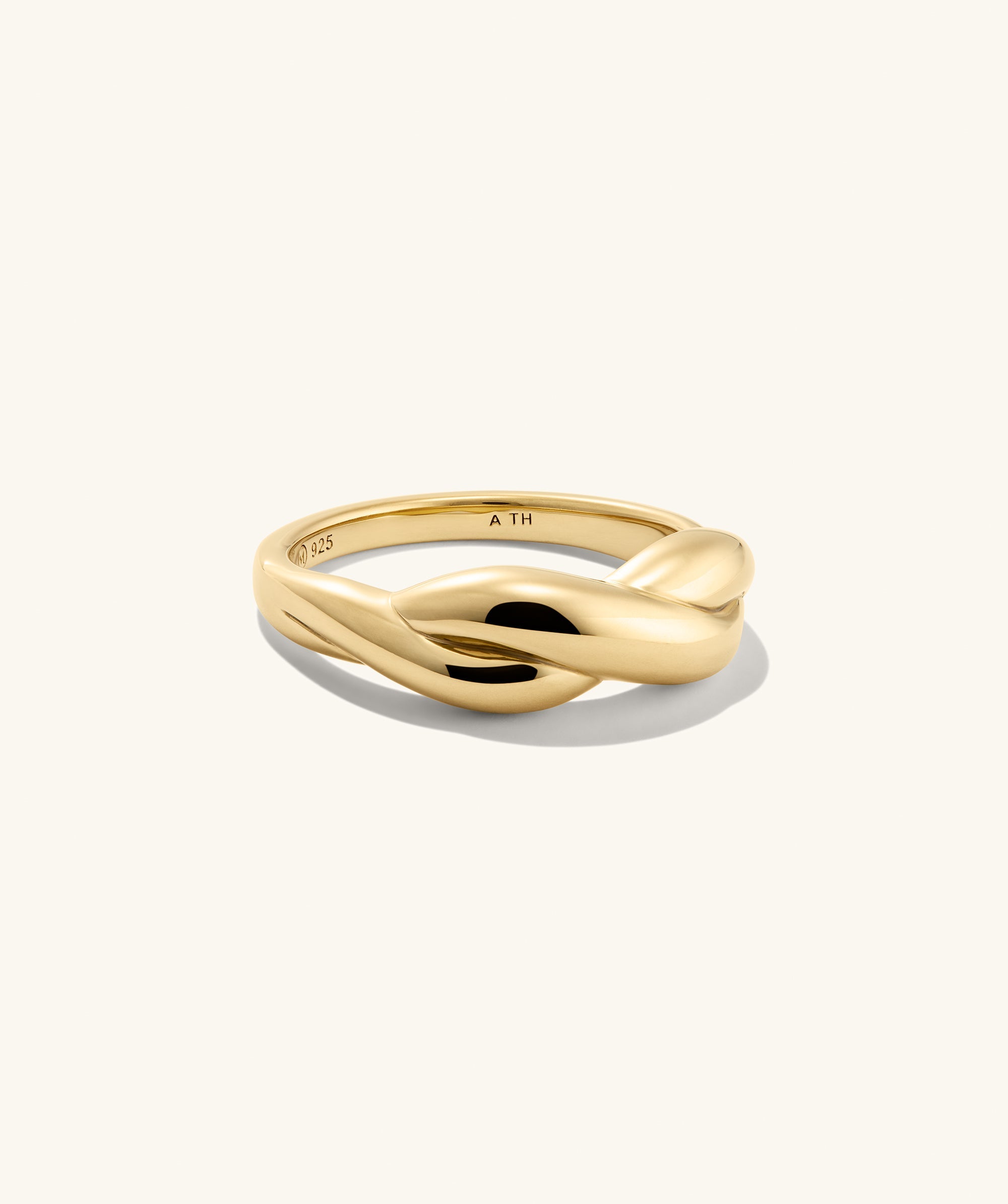 Brioche Ring featuring a polished yellow-gold band with an elegant twist design, presented on a plain background, embodying effortless style and versatility.