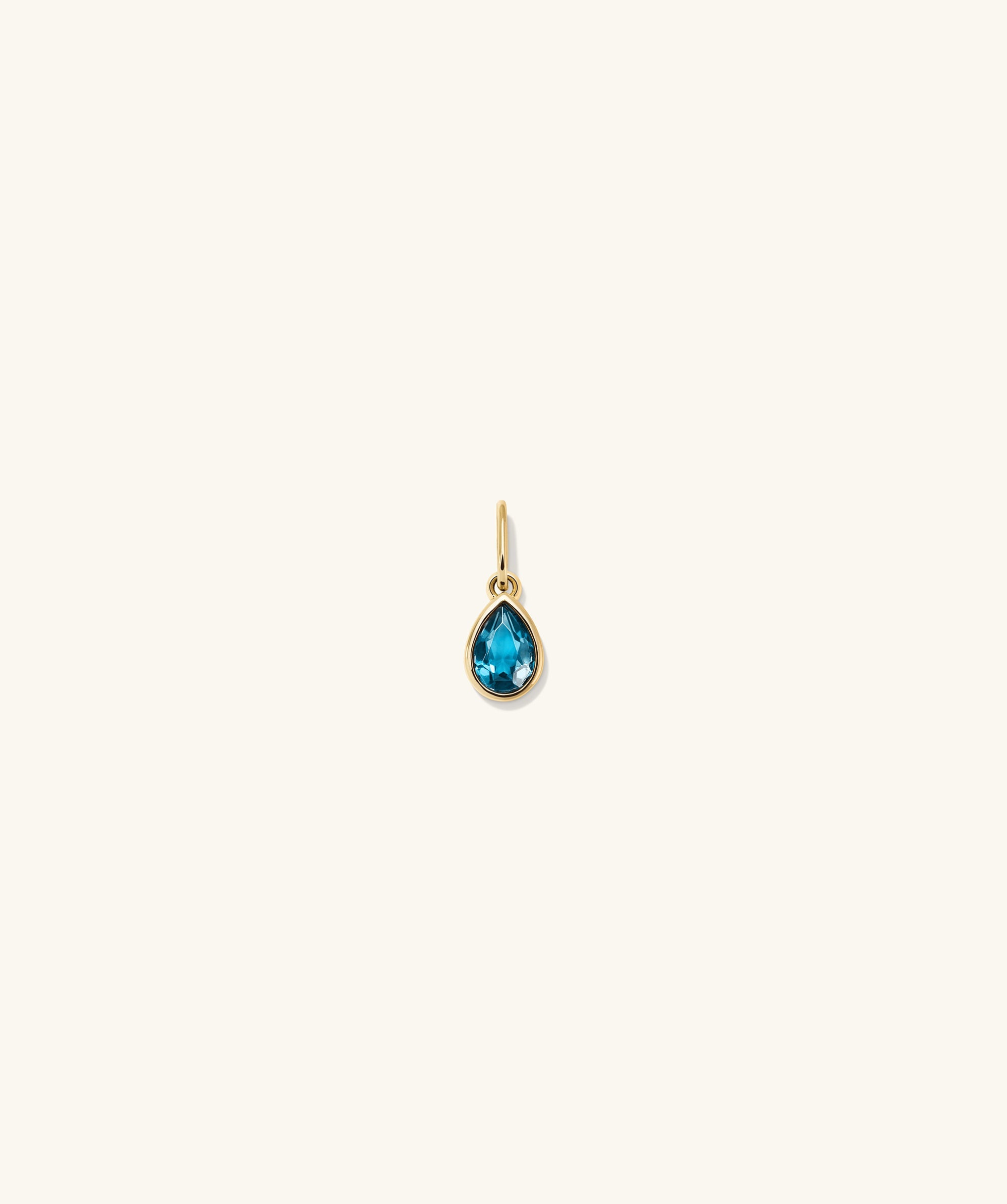 Gold earring featuring a blue gem, showcased as the Small Pear Pendant, adding elegance with its vibrant color and shine.