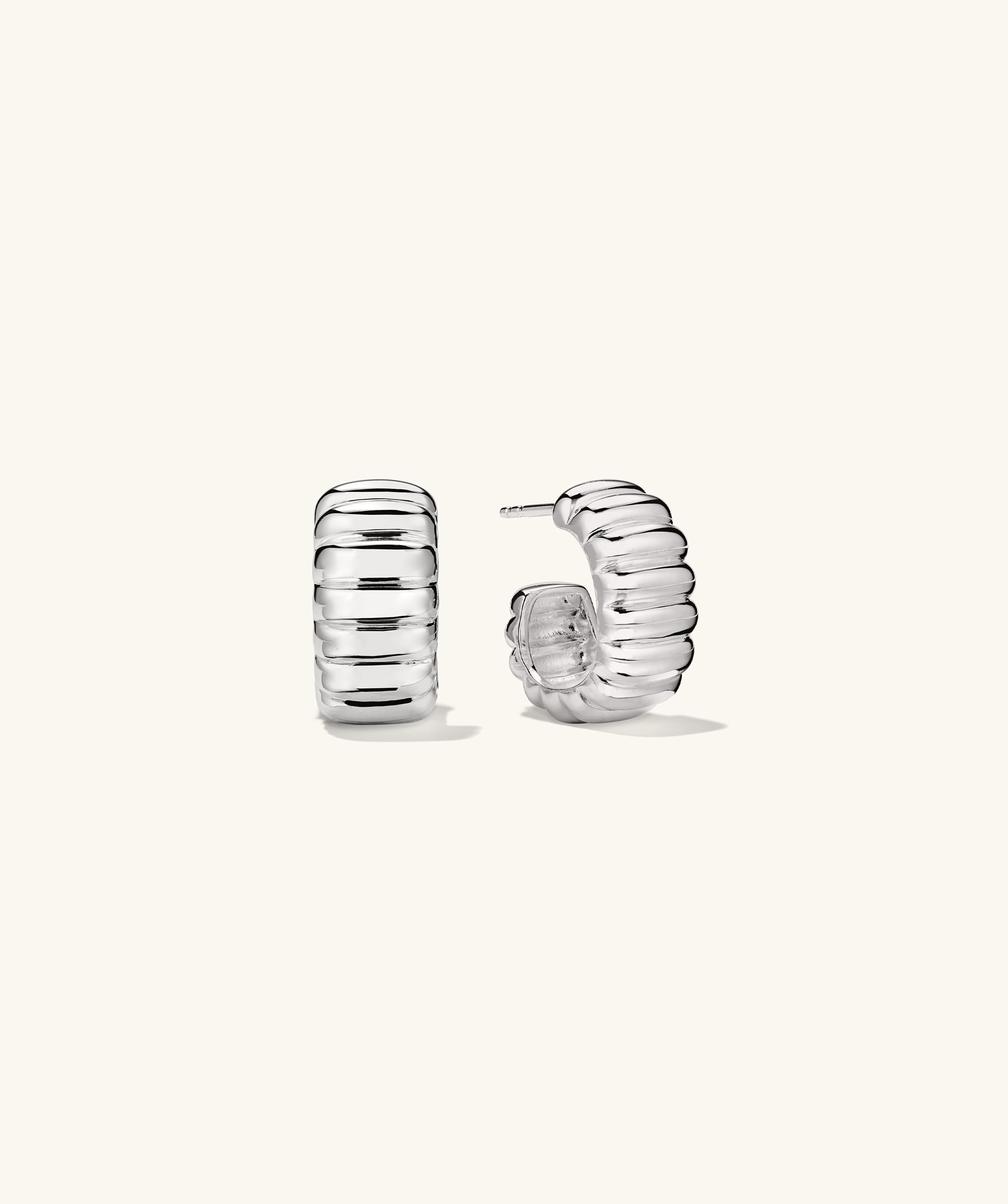 Charlotte Bold Hoops: A pair of silver earrings with a curved design, inspired by French patisserie elegance.