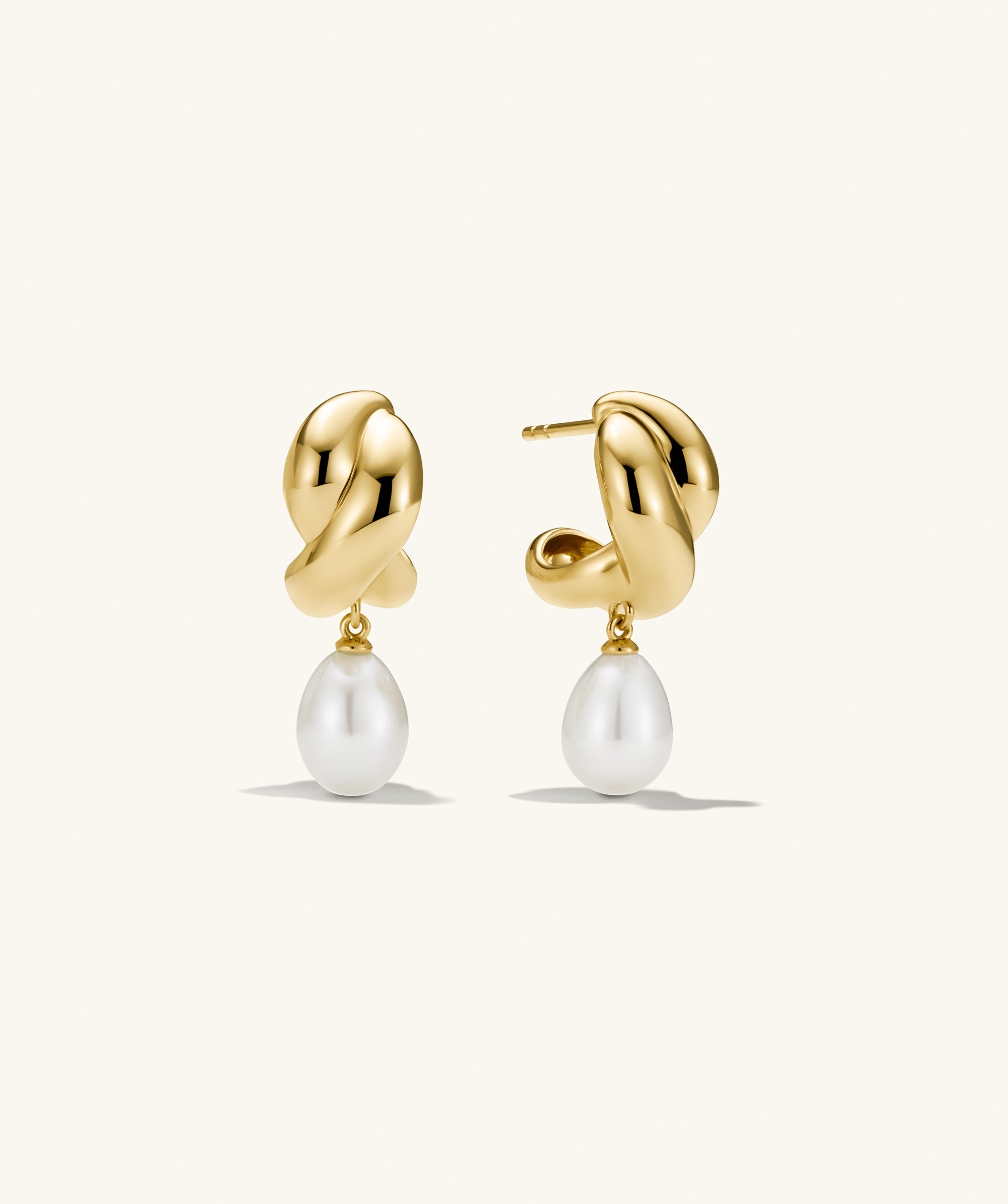Brioche Pearl Drop Earring featuring gold hoops with a pearl charm, showcasing a knot design that offers movement and elegance.