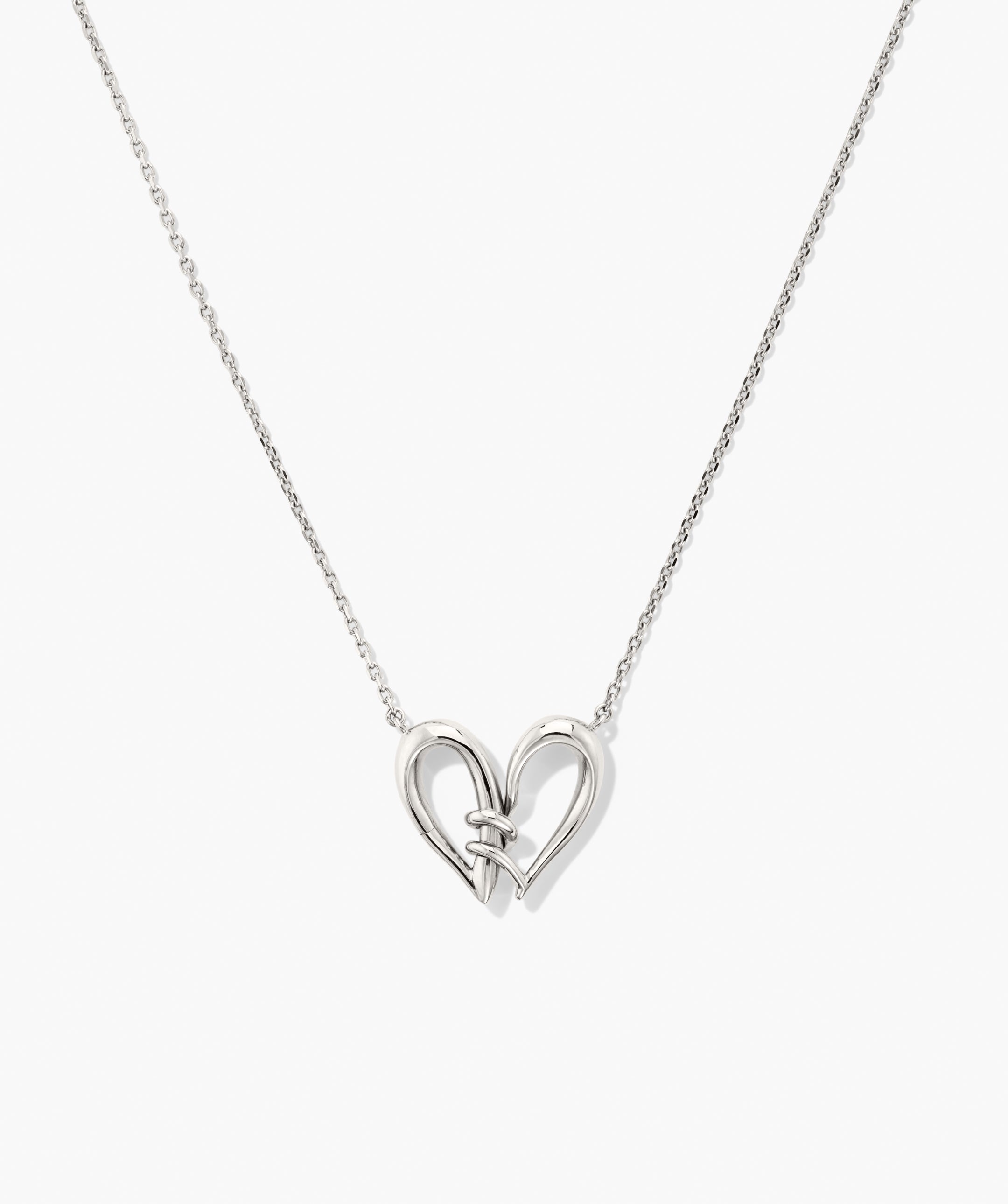Heart to Heart Necklace featuring intertwined tubular silver elements forming an open-heart pendant on a fine chain, showcasing a modern, sculptural design.