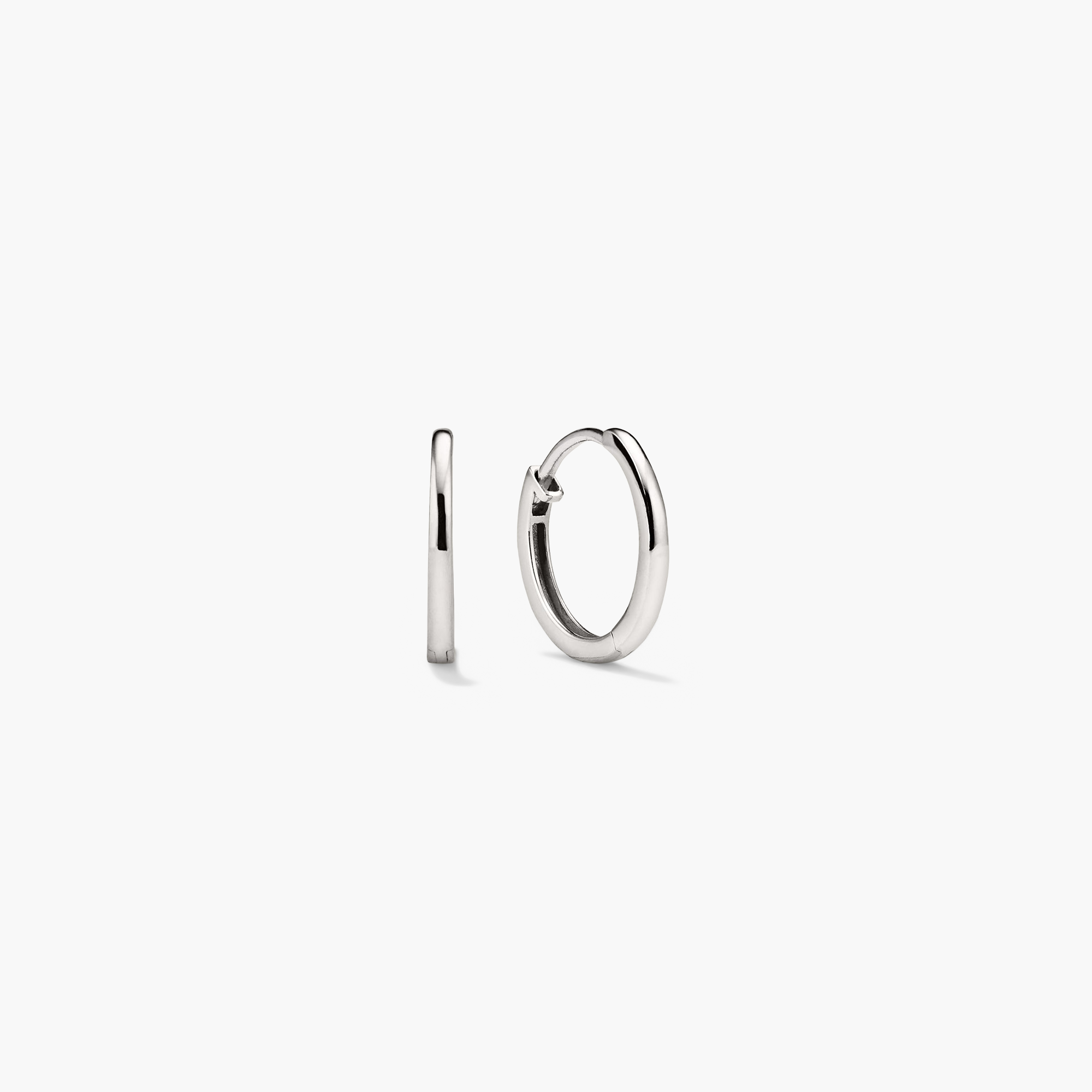 Easy Huggie Hoops: Close-up of a pair of handcrafted, hollowed 14k gold earrings with a secure clicker closure, ideal for everyday wear.