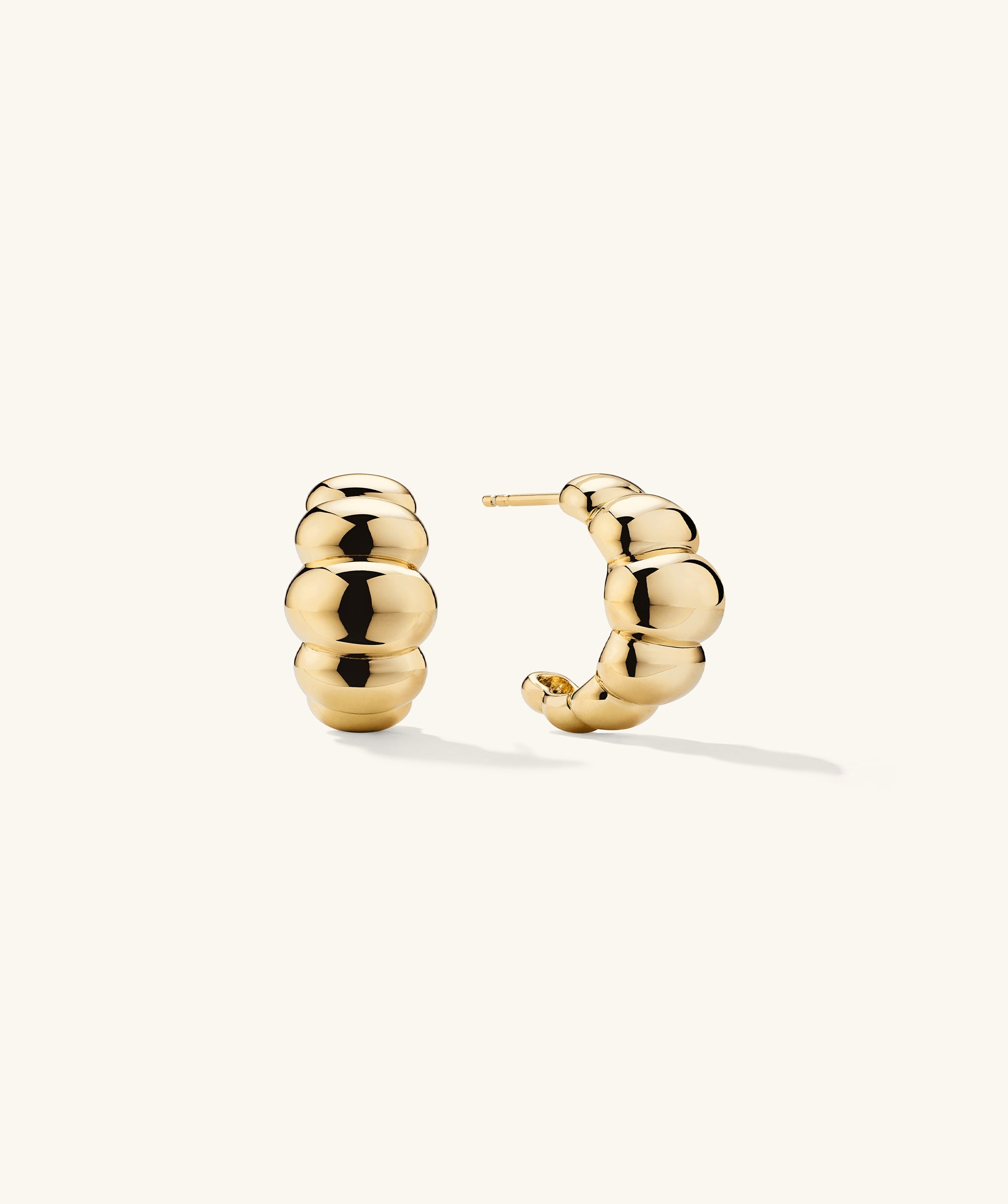 Puffy Charlotte Hoops: a pair of bold, curved gold earrings with a shiny finish, designed to make a statement in the Charlotte Collection.