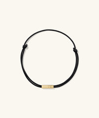 Bar Cord Bracelet featuring a black rope with a sleek gold bar, a versatile fashion accessory that adds a sophisticated touch to any outfit.