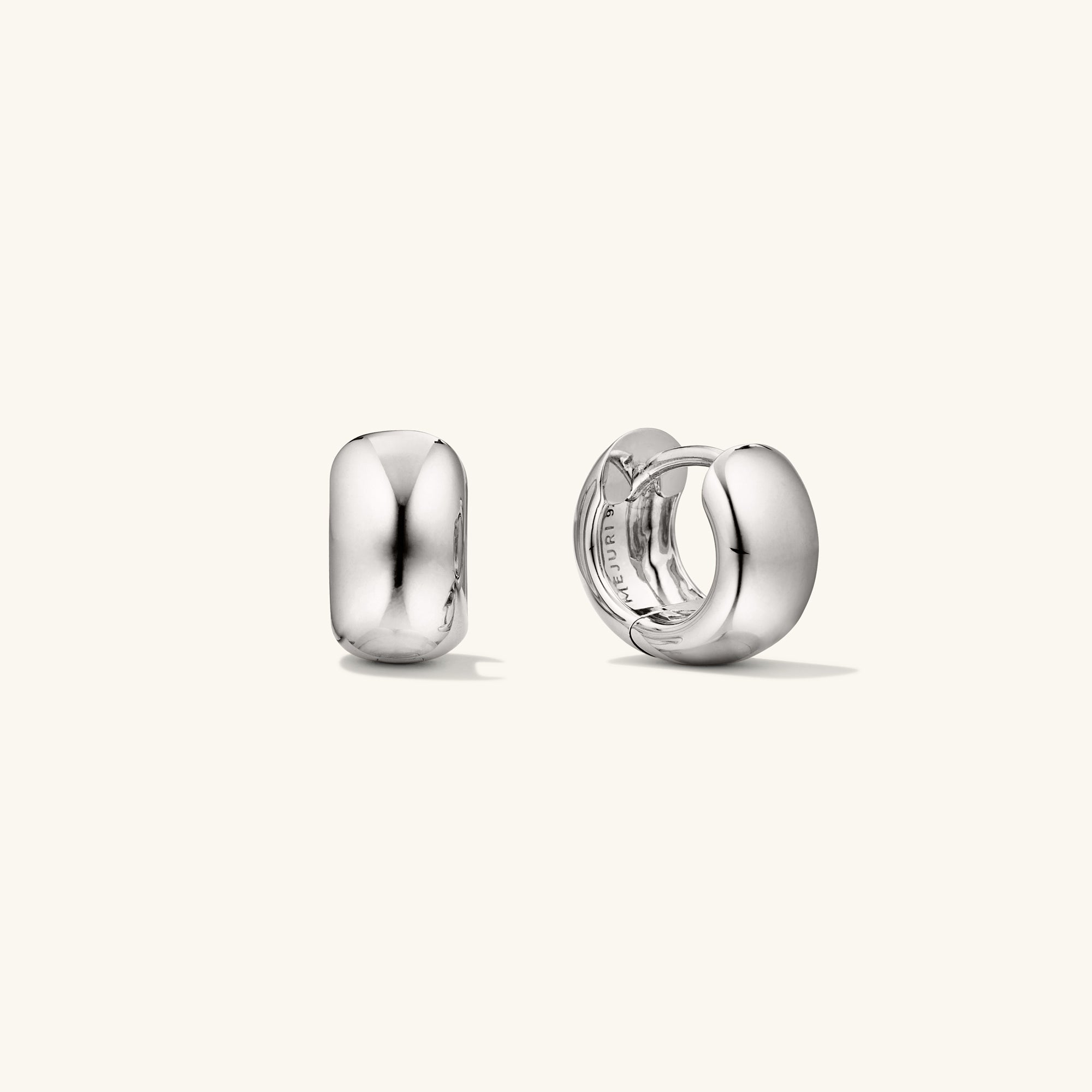 Chunky Huggie Hoops: A pair of silver hoop earrings with a clicker closure, designed for comfort and secure stacking.