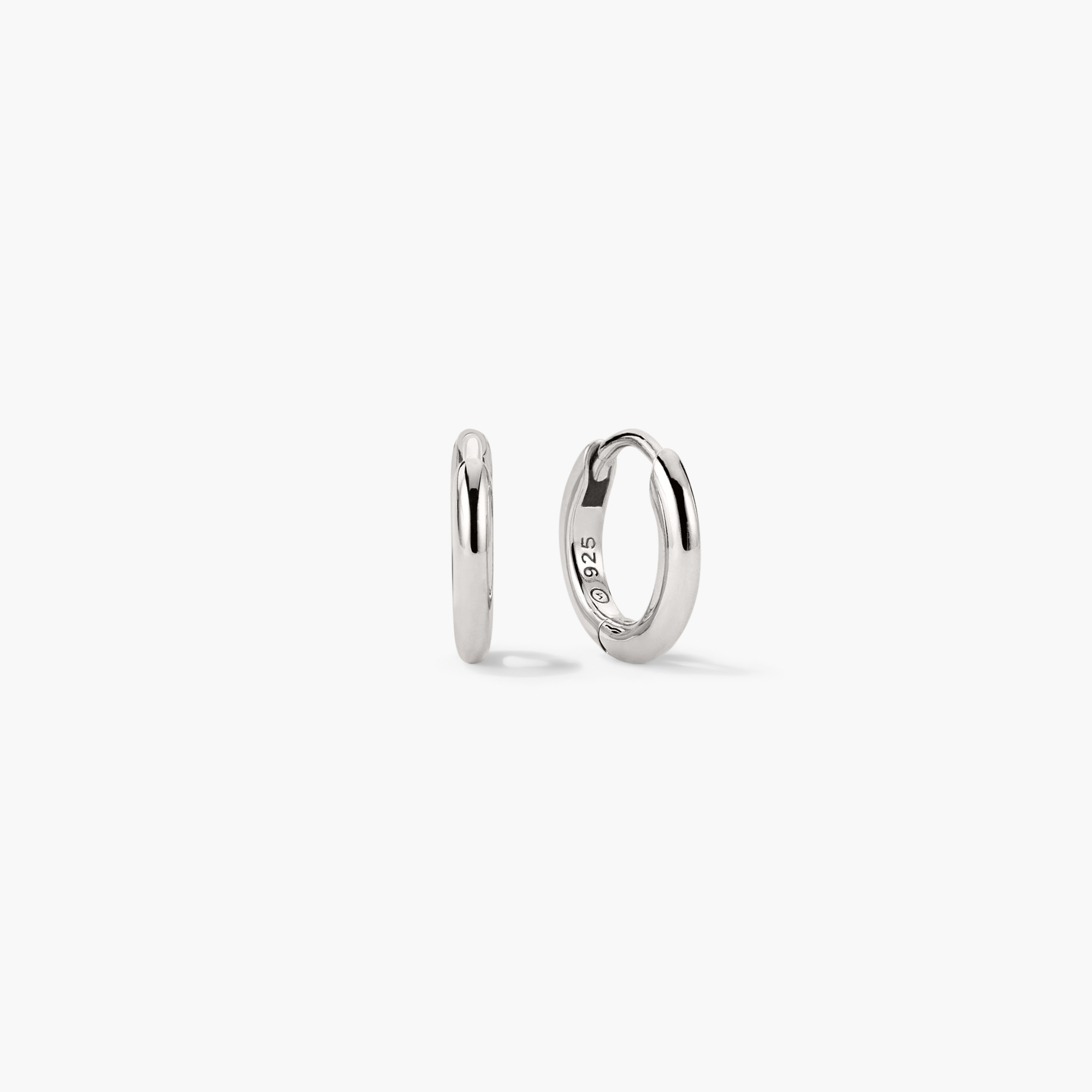 Tube Huggie Hoops: A pair of modern silver hoop earrings with a clicker closure, designed for lightweight, comfortable wear.