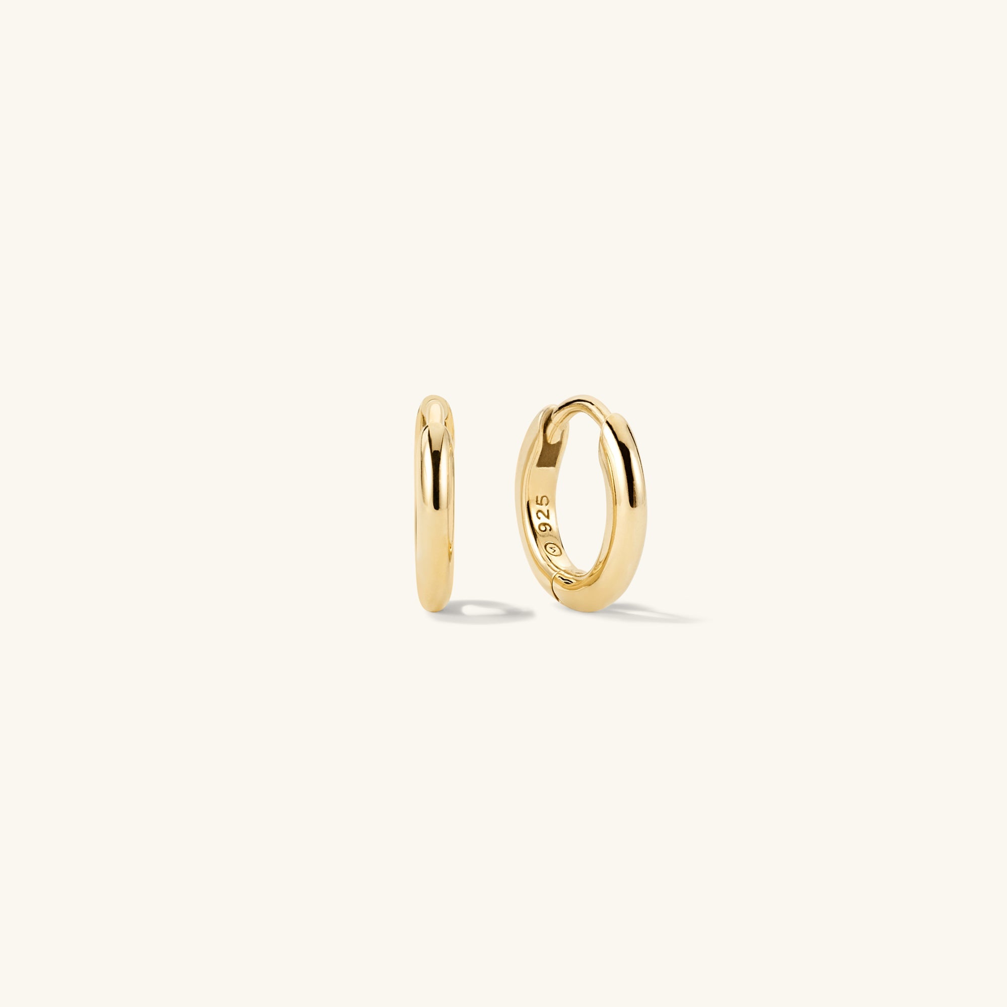 Tube Huggie Hoops: A pair of modern gold hoop earrings with a clicker closure for comfort and security, shown in close-up detail.
