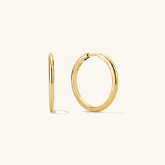 Tube Large Hoops: A pair of modern gold tube hoop earrings with a clicker closure, offering both bold style and lightweight comfort.