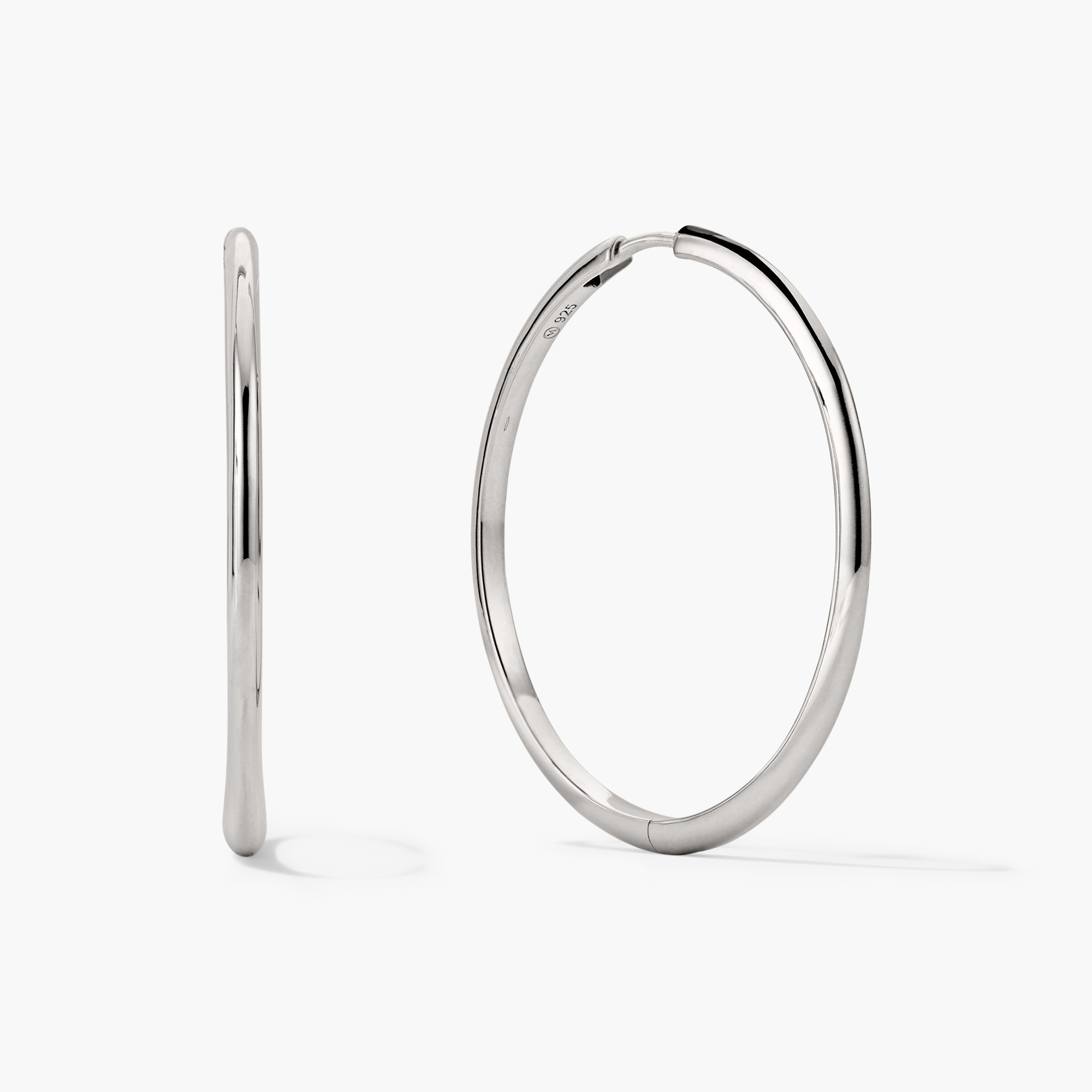 Tube Oversized Hoops: A pair of silver hoop earrings with a sleek, tubular design, featuring a comfortable clicker closure for secure wear.