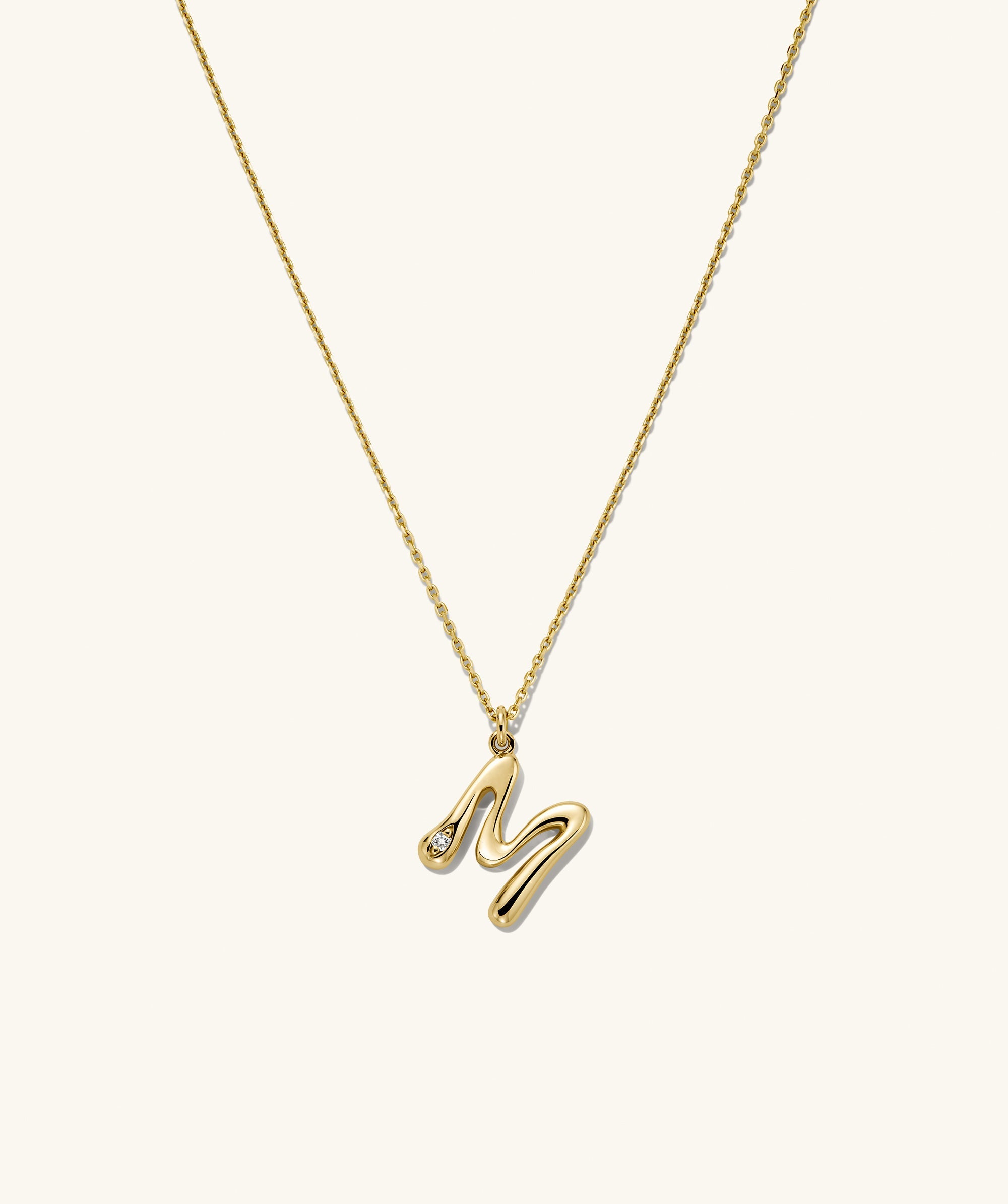 Organic DÃ´me Liquid Letter Pendant Necklace featuring a gold chain with a diamond-accented letter 'M' pendant, highlighting its unique, organic design.