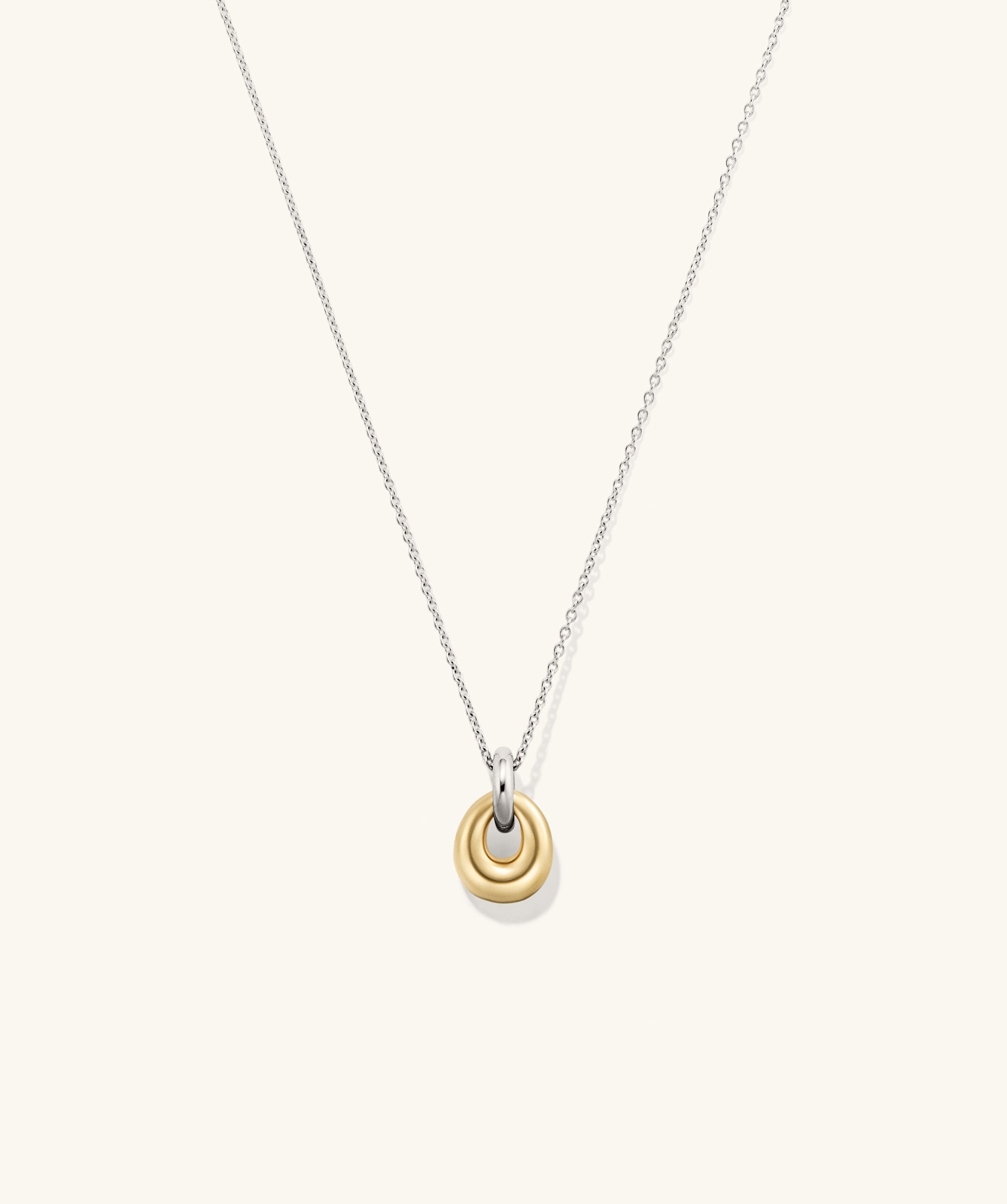 Jojo Loop Pendant Necklace featuring a gold pendant on a silver chain, highlighting its mixed metal design as a fashionable accessory.