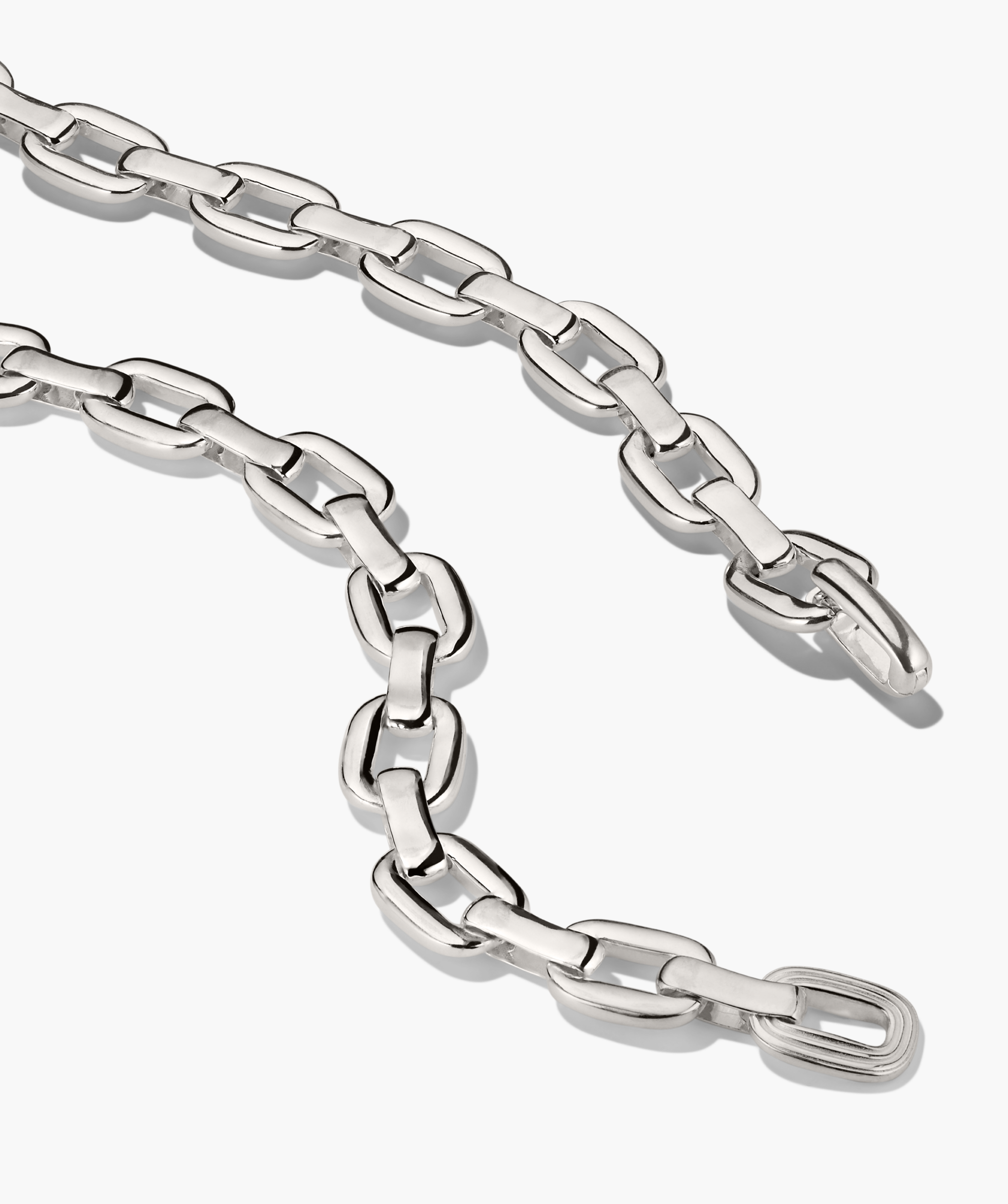 Stevie Chain: Polished silver-tone necklace with interlocking elongated oval links, featuring a single textured link for added interest, laid against a white background.