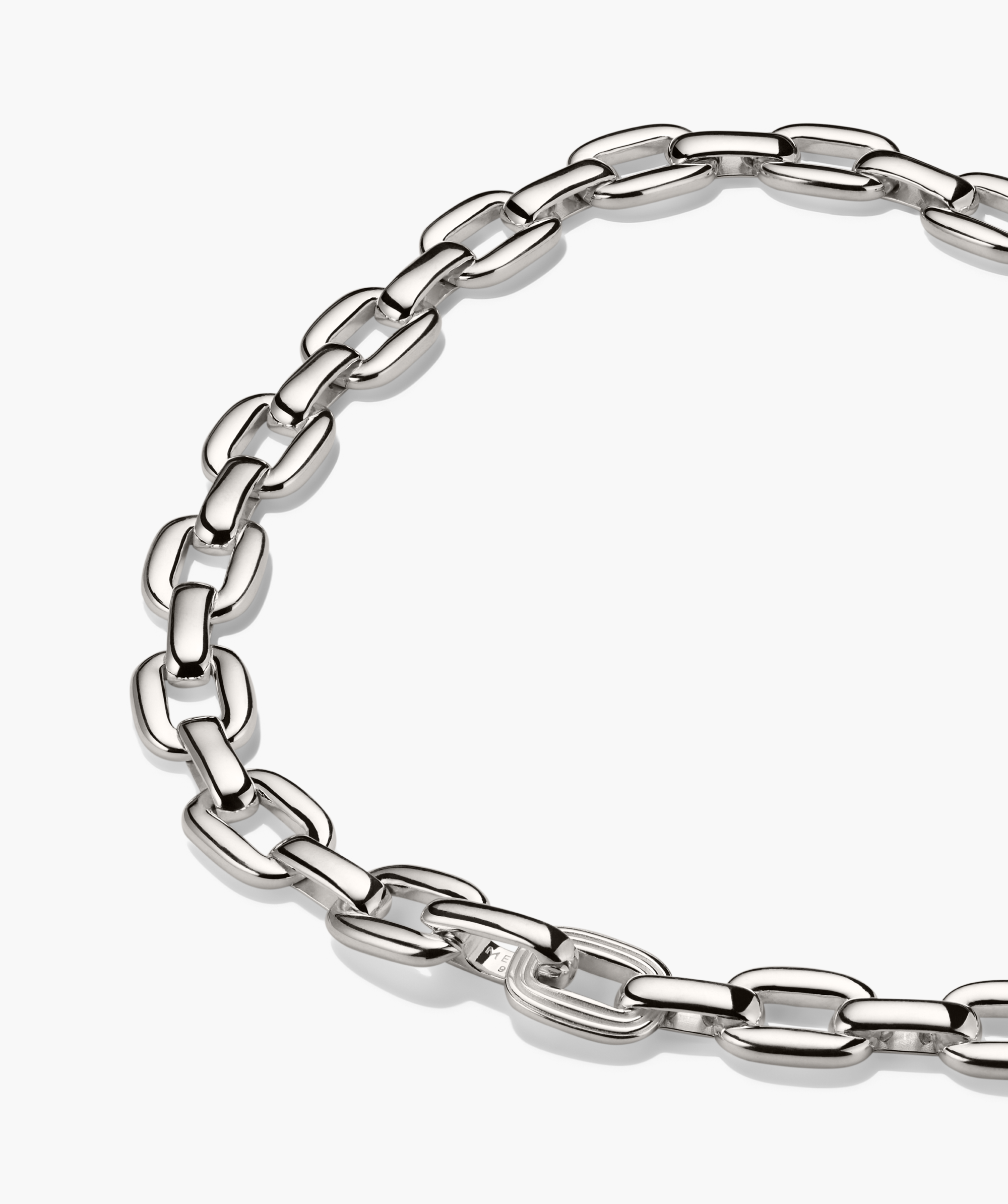 Stevie Chain: Polished silver link necklace with elongated, rounded-rectangle links, featuring a unique textured link for added intrigue, arranged in a loose circle.