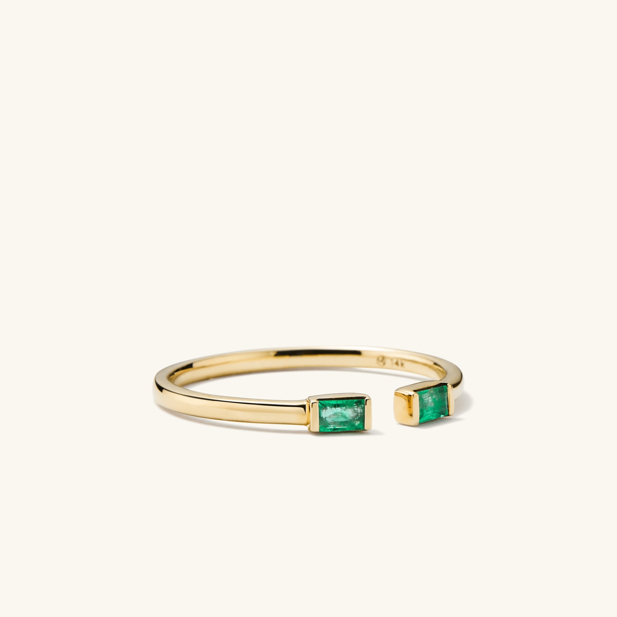 Baguette Emerald Open Ring: A 14k gold ring featuring tapered baguette emerald stones, handcrafted with precise cuts and unique inclusions for distinct character.