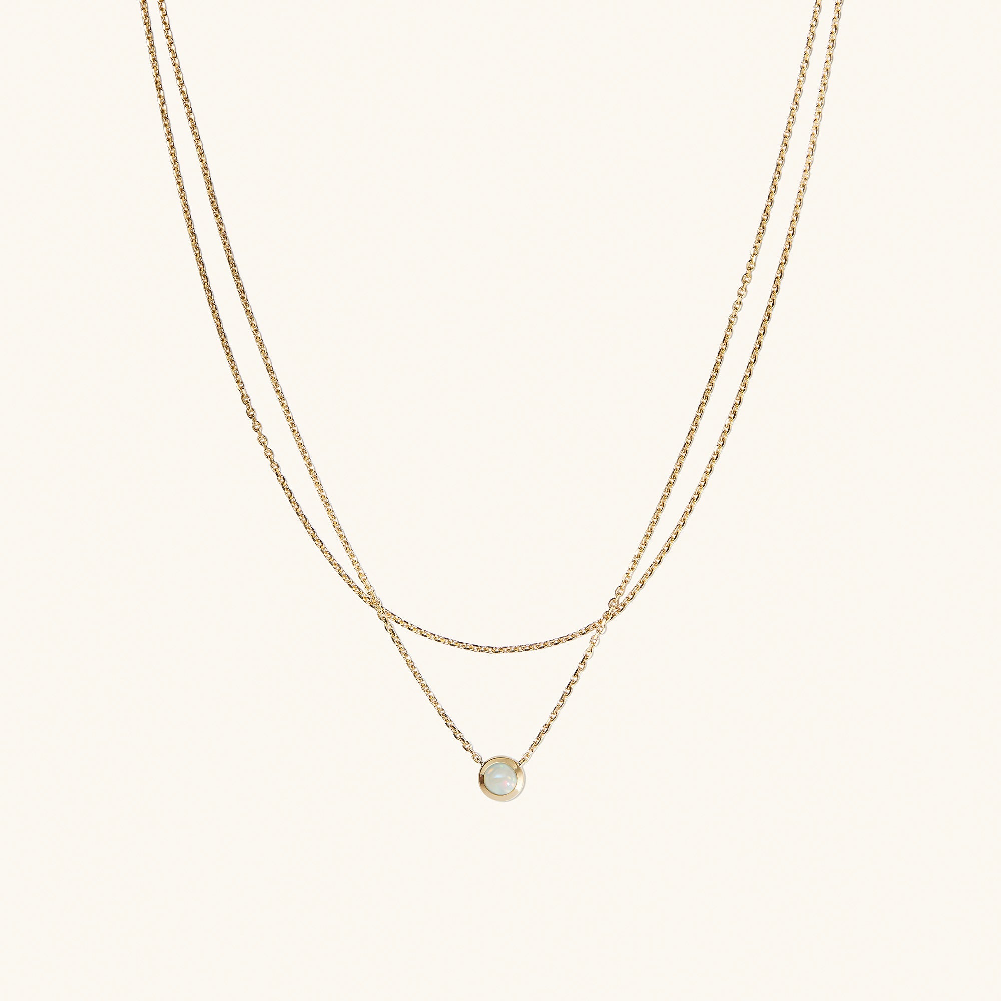 Layered Opal Necklace featuring a gold chain with a small, natural opal pendant.