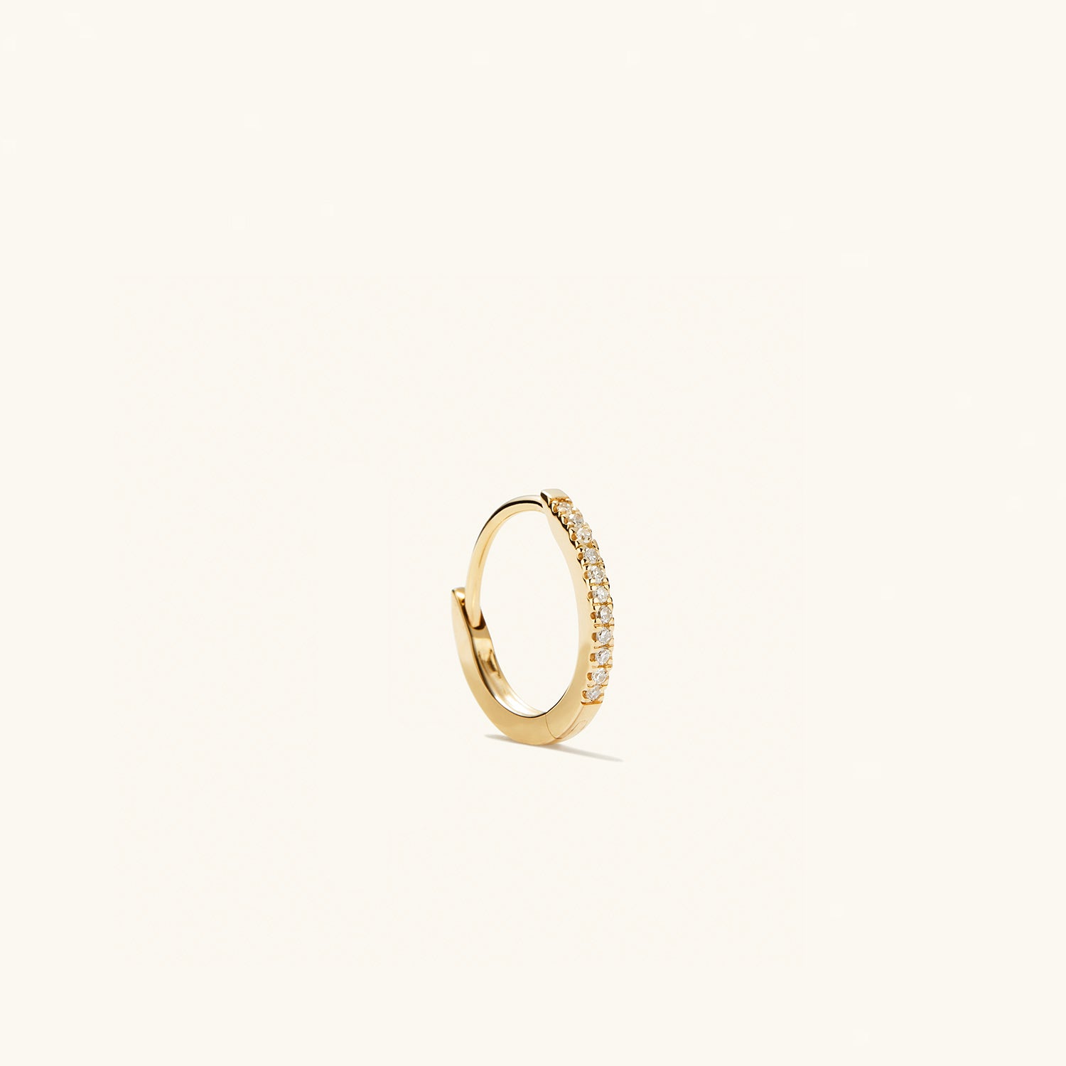 Single PavÃ© Diamond Huggie Hoop: a handcrafted 14k solid gold earring featuring a row of pavÃ© diamonds, designed for versatile wear and elevating any outfit.