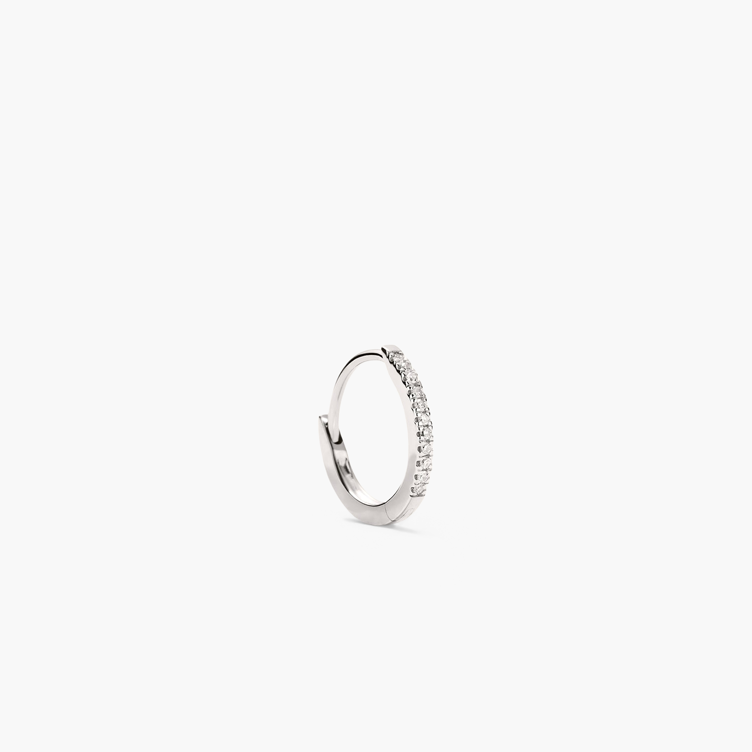 Single PavÃ© Diamond Huggie Hoop: Close-up of a silver earring adorned with diamonds, handcrafted in recycled 14k solid gold, designed for versatile wear.