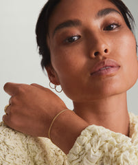 Woman posing, showcasing a sleek, handcrafted 14k yellow gold Timepiece Chain Bracelet on her wrist.